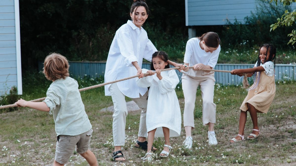 Family playing tug of war in backyard, showcasing teamwork and joy.
